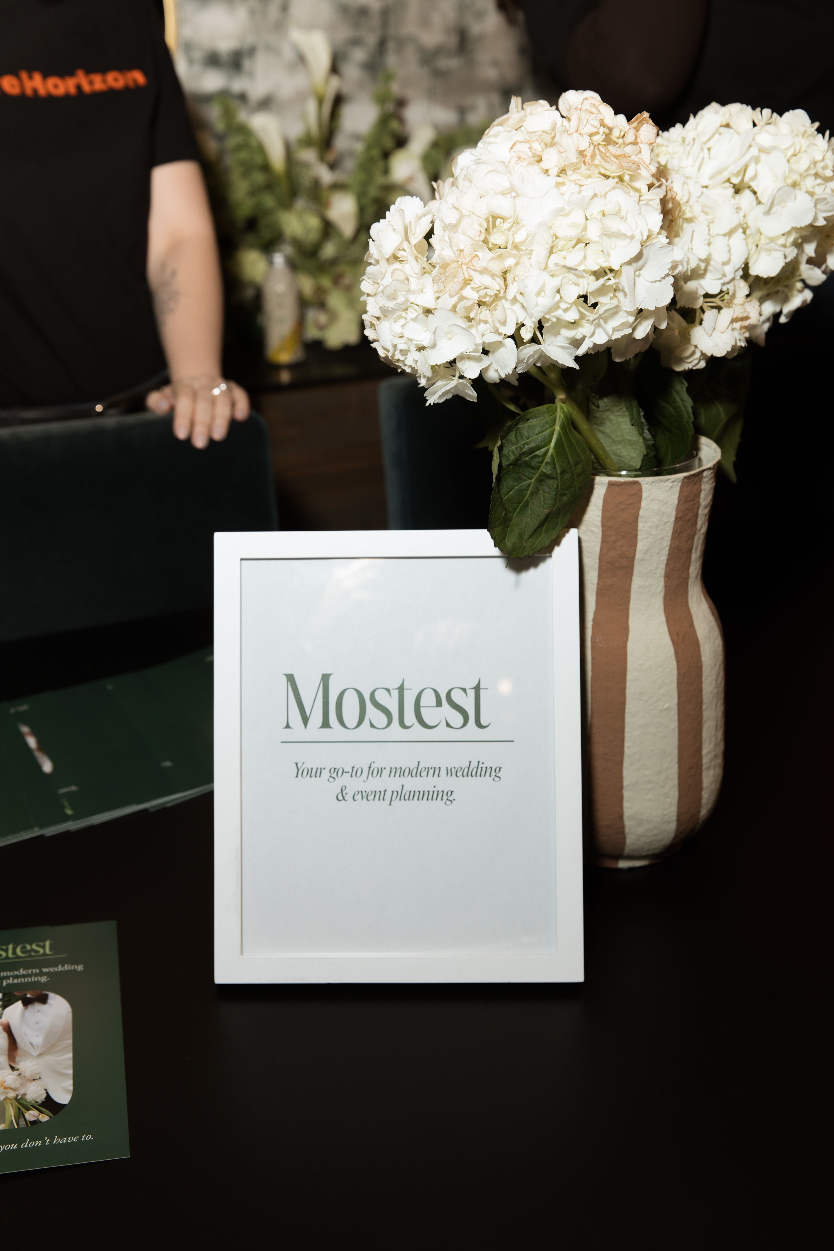 Mostest event planning display with branded signage and white hydrangeas at ISR’s Social Impact House anniversary event.