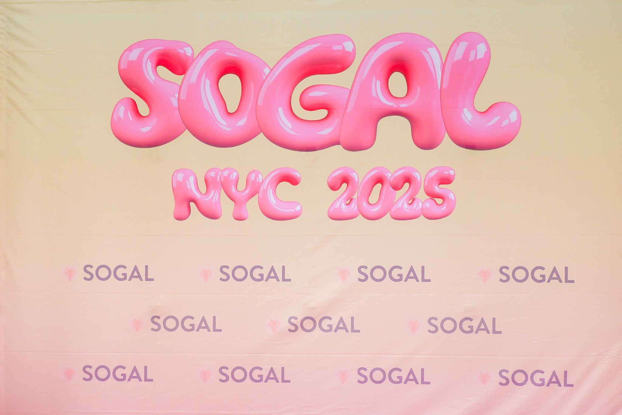 Pink SoGal NYC 2025 event backdrop with bold bubble lettering and repeating SoGal logos.