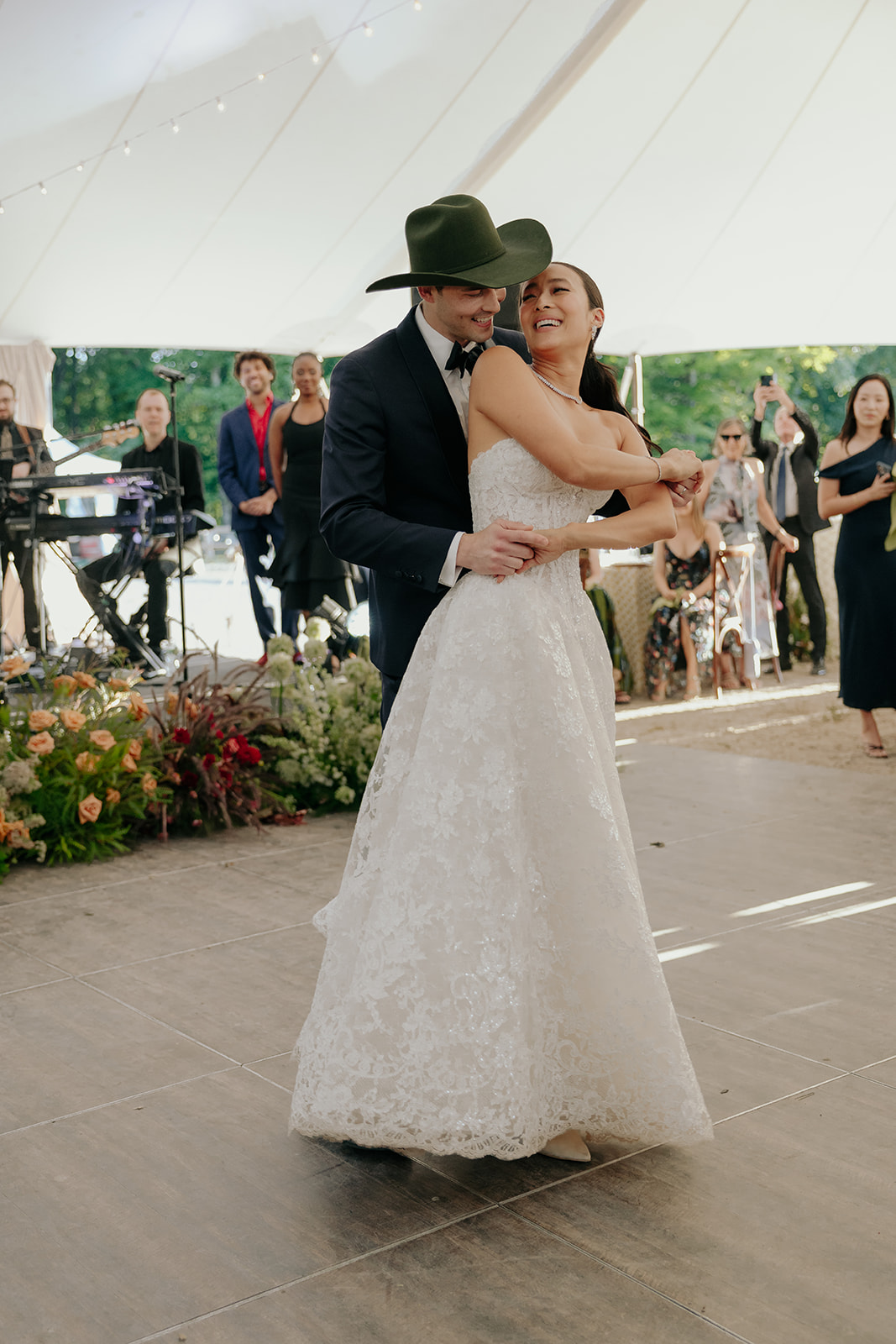 Bride and groom share their first dance beneath a white reception tent at La Luna Farm in New Paltz, New York, surrounded by guests, live music, and floral arrangements.